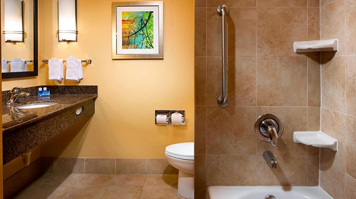 A bathroom attached to one of the guest rooms at the Fairfield Inn & Suites Houston Intercontinental Airport hotel. There's a metal bar attached to the shower wall to ensure safe entrance and exit.