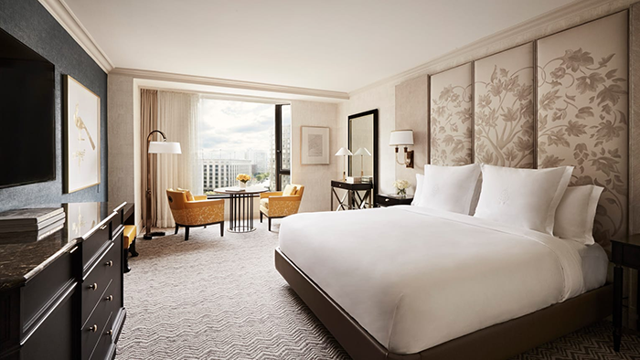 A guest room at the Four Seasons Hotel Boston with a large bed, a seating area, and a window overlooking the city.