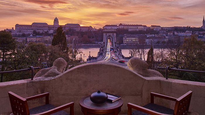 The view from a higher floor at the Four Seasons Hotel Gresham Palace Budapest, featuring a sunset above the picturesque Buda skyline just past the Danube River.