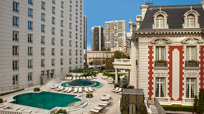 The exterior of the Four Seasons Hotel Buenos Aires, where an early 1900s mansion is combined with a modern highrise. A pool is visible between the two structures.