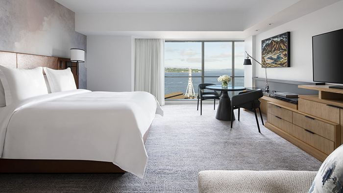 A guest room at the Four Seasons Hotel Seattle. The room is spacious, with a large bed and a floor-to-ceiling window overlooking Elliott Bay.