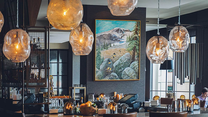 A bar at the Four Seasons Hotel Seattle. A painting of a mountainous landscape hangs above the bar.