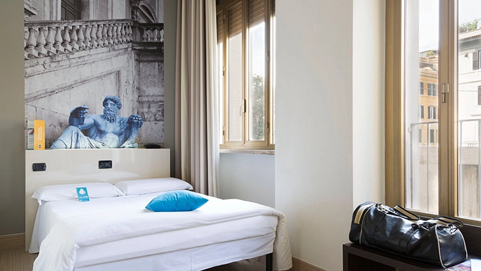 A guest room in the B&B Hotel Roma Trastevere. An image of an ancient Roman statue hangs above the bed.