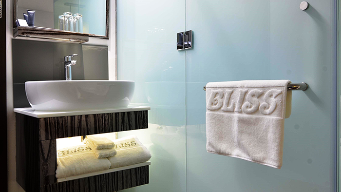 A guest bathroom at the Bliss Hotel Singapore featuring towels with an embossed Bliss logo.