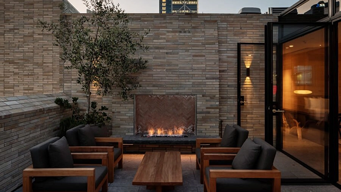 A common area with seating at The Hotel Britomart. An outdoor fireplace is lit.