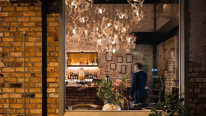 A bar inside The Hotel Britomart in Auckland, New Zealand. An ornate lighting fixture is hanging from the ceiling.
