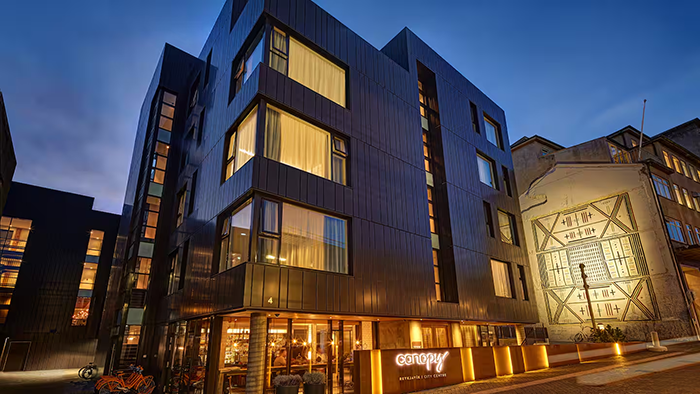 The exterior of the Canopy by Hilton Reykjavik City Centre. A mural is seen on the side of the building to the right of the hotel.