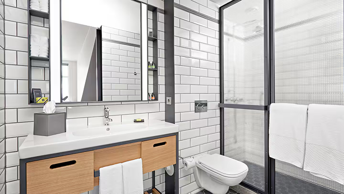 A guest bathroom inside the Canopy by Hilton Reykjavik City Centre. The walls are covered in rectangular white tile.