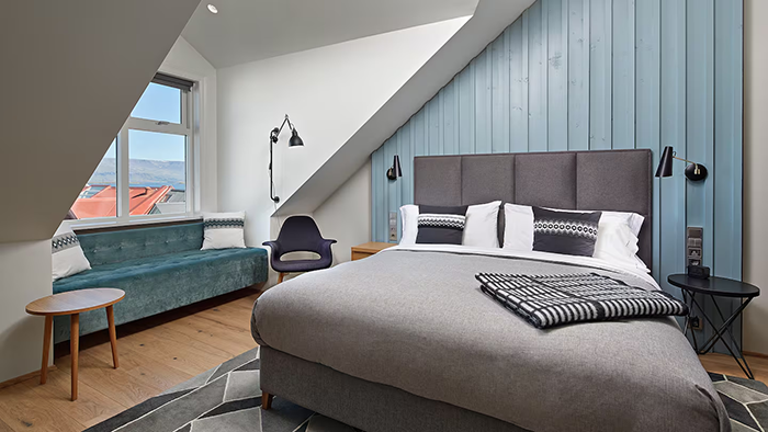 A guest room at the Canopy by Hilton Reykjavik City Centre. There's a cool blue accent wall just behind the bed's headboard.