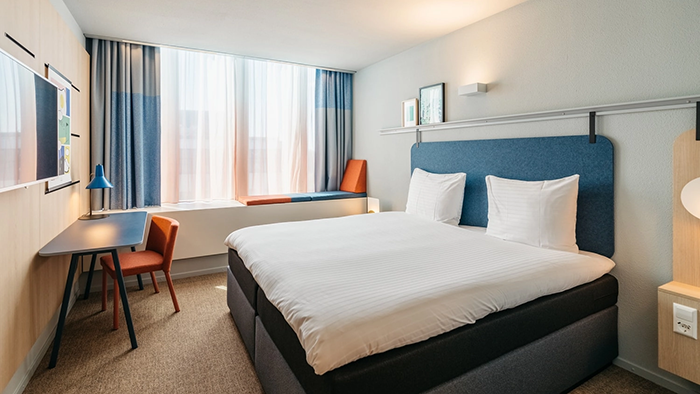 A guest room inside the Hotel Casa Amsterdam. It's decorated in a modern style with blue and orange accents.