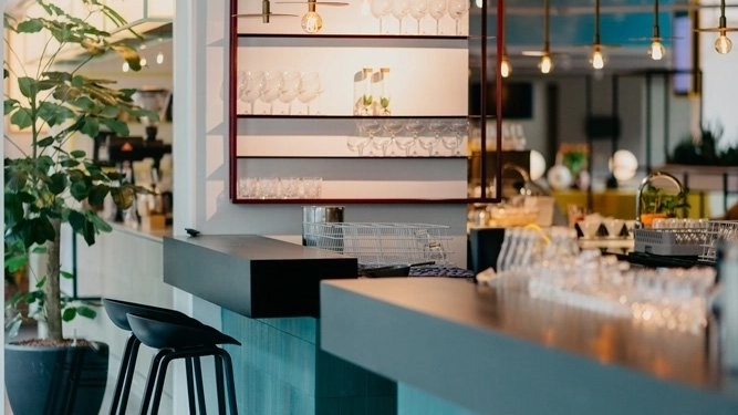 A cafe inside the Hotel Casa Amsterdam. Clean glasses sit on a shelf behind the bar.