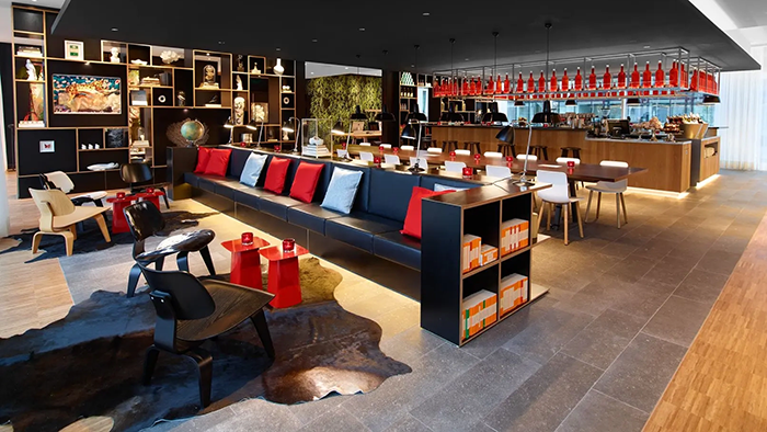 A common area with seating inside the citizenM Rotterdam hotel. A bar is visible in the background.
