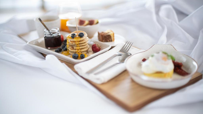 Breakfast in bed at the Coco-Mat Athens BC hotel featuring a stack of miniature pancakes.