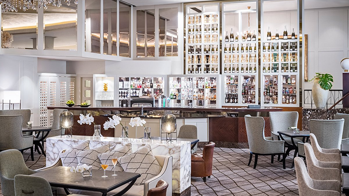 A bar inside the Cordis, Auckland hotel. There looks to be an extensive champagne selection above the other bottles behind the bar.