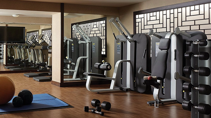 The fitness center inside the Cordis, Auckland hotel. A set of free weights waits on a rack to the right of the frame.
