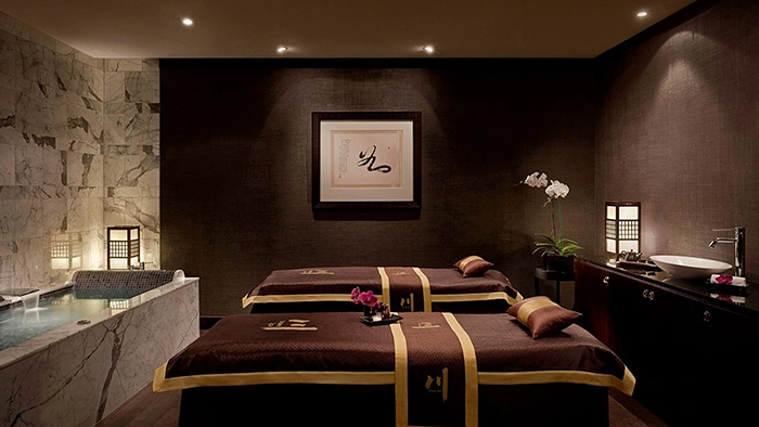 A massage room inside the Cordis, Auckland hotel. A marble bathtub is visible on the left side of the room.