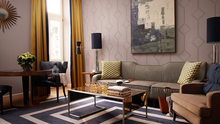 A guest suite at The Corinthia Budapest Hotel. An abstract painting hangs from a wall covered in an interesting geometric wallpaper.