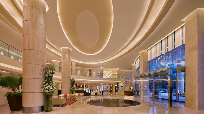 The lobby of the Courtyard by Marriott Mumbai International Airport Hotel. Giant pillars provide support for the exceptionally high ceiling.