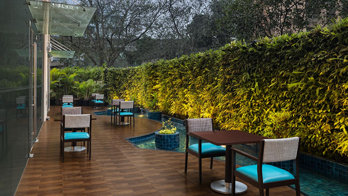 An outdoor seating area at the Courtyard by Marriott Mumbai International Airport Hotel. A lovely hedge gives guests privacy from the outside world.