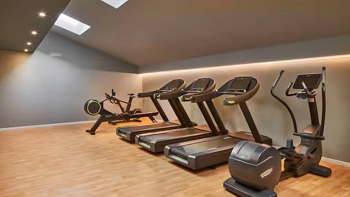 The DoubleTree by Hilton Trieste hotel's fitness center. Three treadmills, an elliptical, and a standing bike are all present.