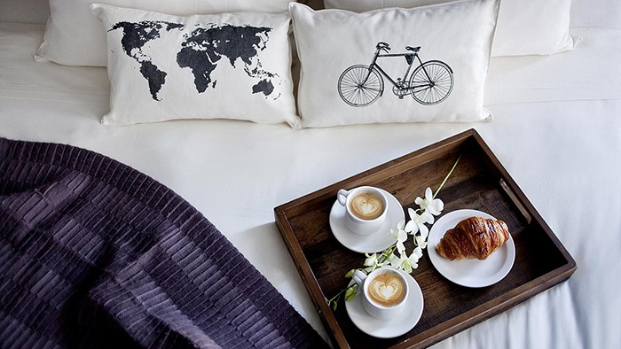Breakfast served in bed at the Htel du Vieux-Qubec. Two printed pillows are shown, one featuring the world map and another featuring a bicycle.