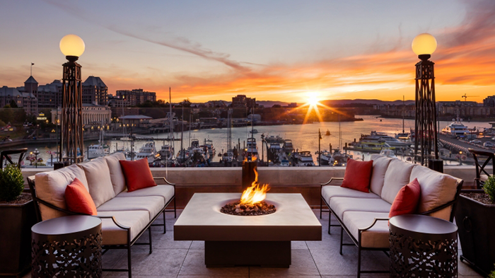 A terrace at the Fairmont Empress hotel. Victoria Harbour and a beautiful sunset are both visible in the background.