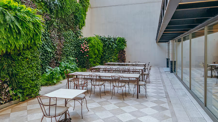 An outdoor seating area at the Esplendor by Wyndham Buenos Aires Tango Hotel. A wall of greenery livens up the patio.