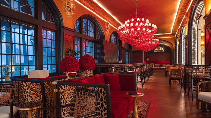 A bar area inside the Grand Galvez hotel. The room is extremely red, with two red hanging chandeliers.