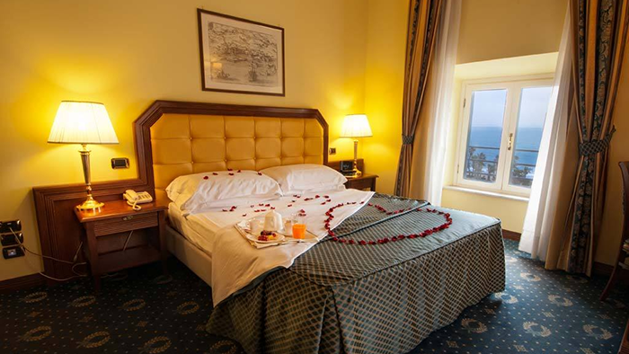 A guest room at the Hotel San Giorgio. A full breakfast tray sits on the bed, as does a heart made of rose petals.