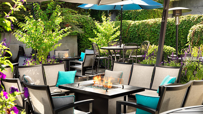 An outdoor common area at the Hotel Grand Pacific in Victoria. There's a couple fireplaces and lots of greenery.