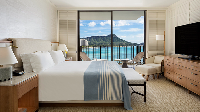 A guest room at the Halekulani Hotel in Honolulu. A beautiful Hawaiian landscape is visible through the floor-to-ceiling window.