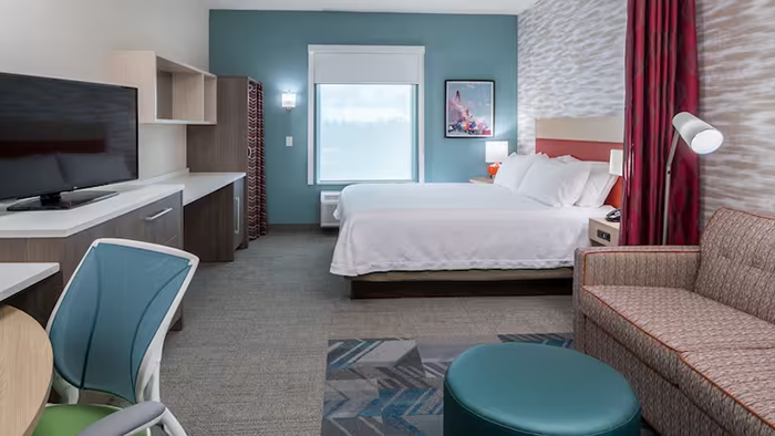 A guest room at the Home2 Suites by Hilton Cape Canaveral Cruise Port hotel. The right side of the image features an interestingly patterned couch.