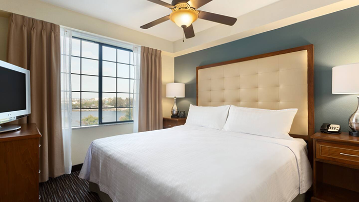 A guest room at the Homewood Suites by Hilton San Diego Airport-Liberty Station hotel. A view of the San Diego Bay can be seen through the window.