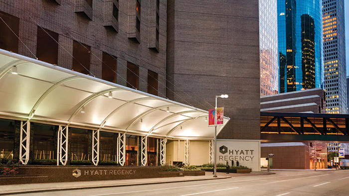 The exterior of the Hyatt Regency Houston hotel. There are two Hyatt Regency logos on the front of the building.