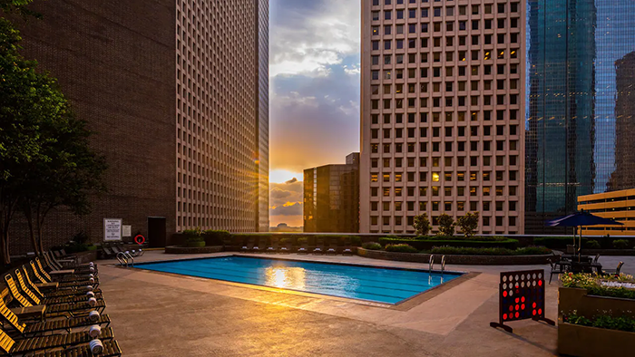 The rooftop pool at the Hyatt Regency Houston hotel. A sunset is visible behind some clouds and the Houston cityscape.