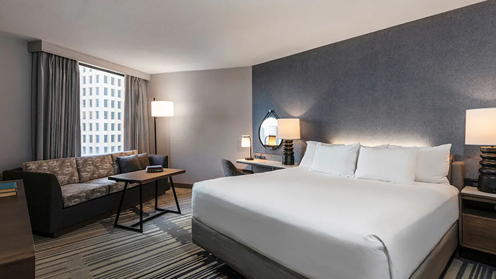 A guest room at the Hyatt Regency Houston hotel. There's a slate blue accent wall behind the bed's headboard.
