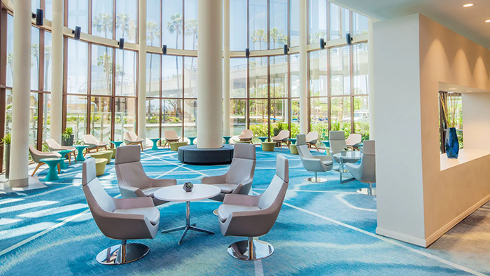 An interior section of the Hyatt Regency Long Beach hotel with tons of seating and plentiful natural light coming through the panoramic windows.