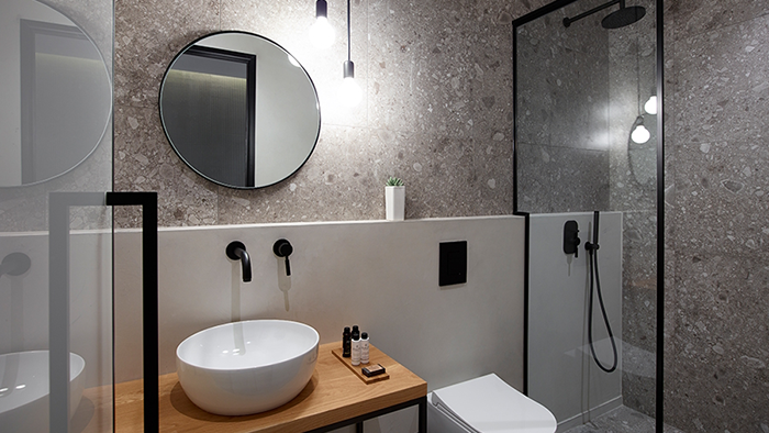 A guest bathroom at in[n]Athens hotel sporting a modern design and a small succulent plant.