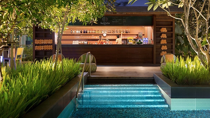 A poolside bar at JEN Singapore Orchardgateway Hotel by Shangri-La. Two employees wearing vacation-style shirts are on duty.