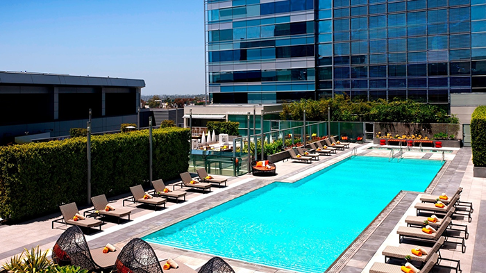 The rooftop pool at the JW Marriott Los Angeles L.A. LIVE hotel. The edges of the water are dotted with lounge chairs ideal for suntanning.