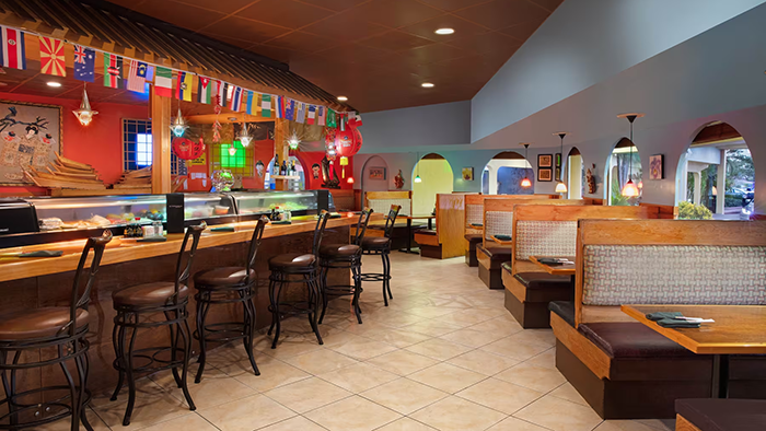 A restaurant inside the La Quinta Inn by Wyndham Cocoa Beach-Port Canaveral. There's plenty of booth seating available, as well as some seats at the bar.