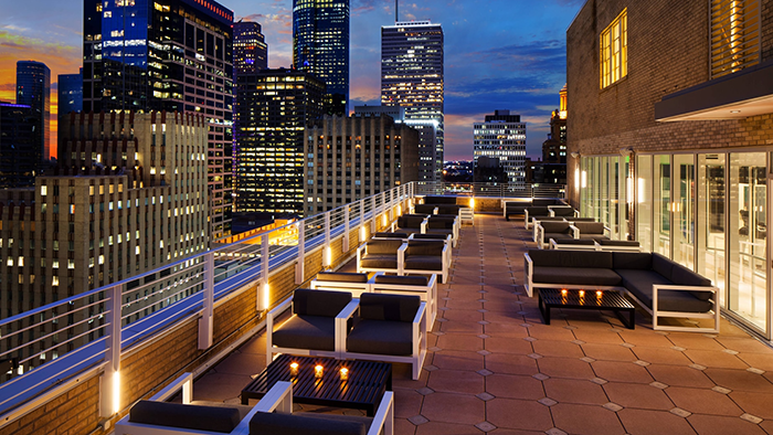 An outdoor common area on a rooftop at the Le Mridien Houston Downtown hotel. The Houston skyline is visible in the background.