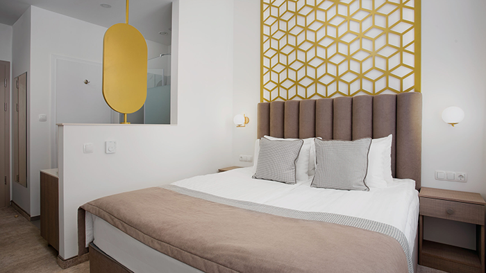 A guest room at the Mera Hotel in Budapest, Hungary. The room features mostly neutral colors, with gold accents being the only exception.