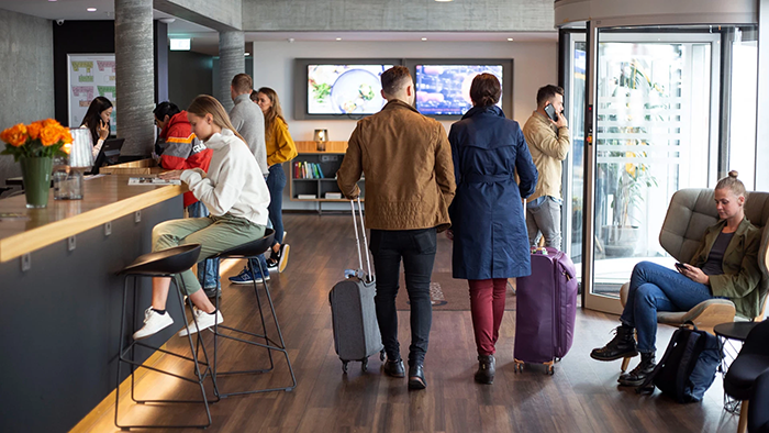 The main lobby inside Midgardur by Center Hotels in Reykjavik. Numerous guests with suitcases are seen coming and going.