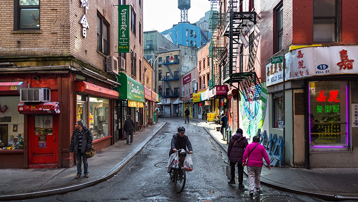 People walking and biking through the Big Apple's famous Chinatown.