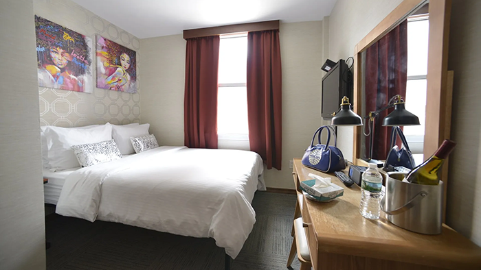 A guest room at the Hotel Mimosa. A bottle of wine and a bottle of water are both sitting on a table on the right side of the image.