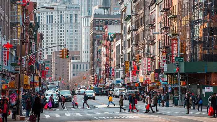 Pedestrians crossing a large street in New York City's Chinatown near the Hotel Mimosa.
