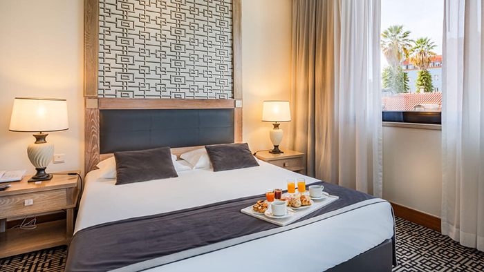 A guest room at the Hotel Mundial. A tray of breakfast items and beverages is sitting at the foot of the bed.