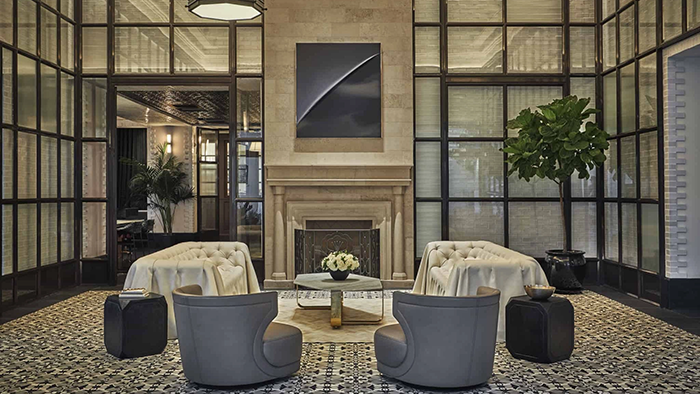A common area inside the Hotel Pendry in San Diego. A small arrangement of white roses sits on a coffee table in front of a fireplace.