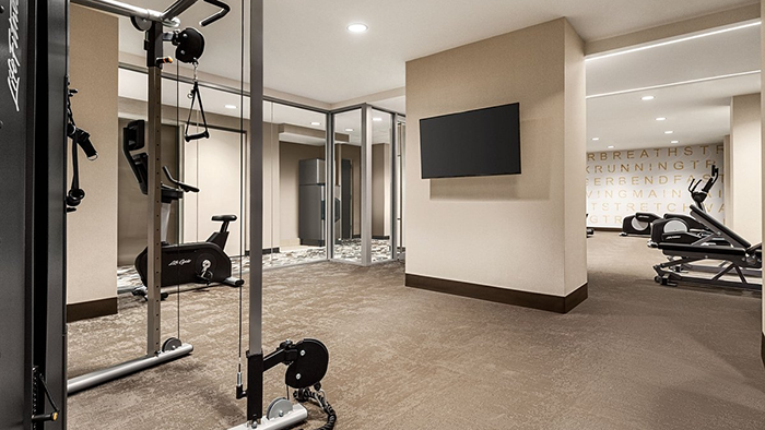 The fitness center located inside the Residence Inn by Marriott New York JFK Airport. A medium-sized flatscreen TV hangs from the wall.